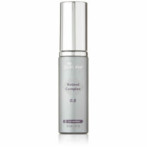 A silver and white dispenser bottle of skinmedica retinol complex 0.5 standing upright on a white background. the label displays the product name and mentions it is for age defense.