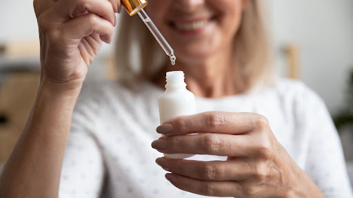 Older woman with retinol in dropper from Lincoln medi spa.